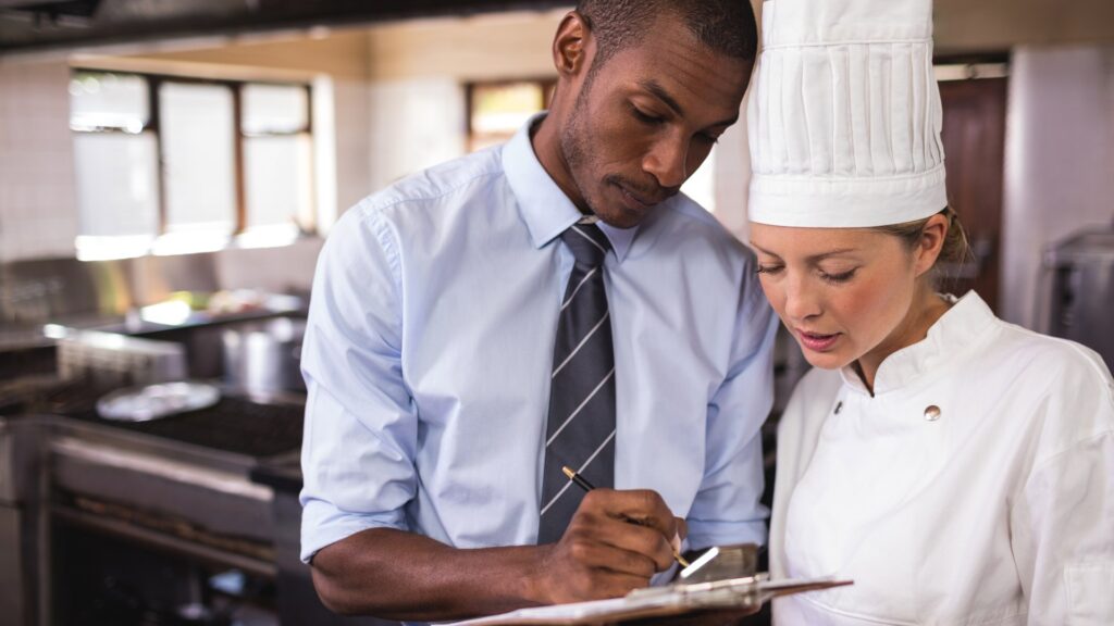Coste de personal en restaurantes: responsable y jefa de cocina revisando el equipo con el cuadrante