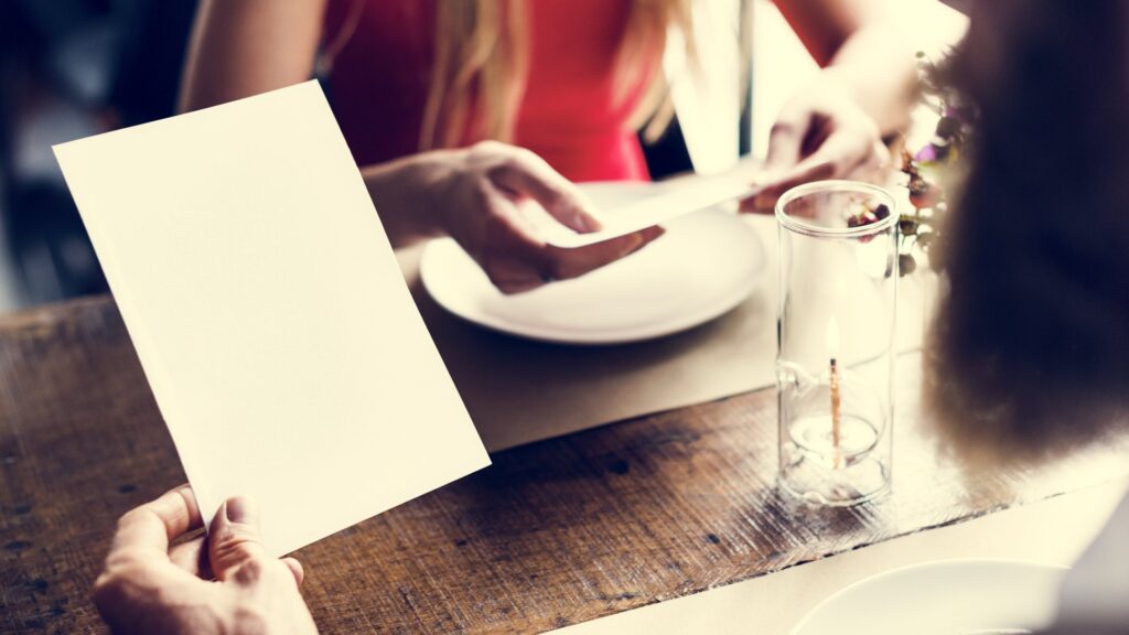Mesa de restaurante con comensales y carta, el ticket medio en restaurantes en juego