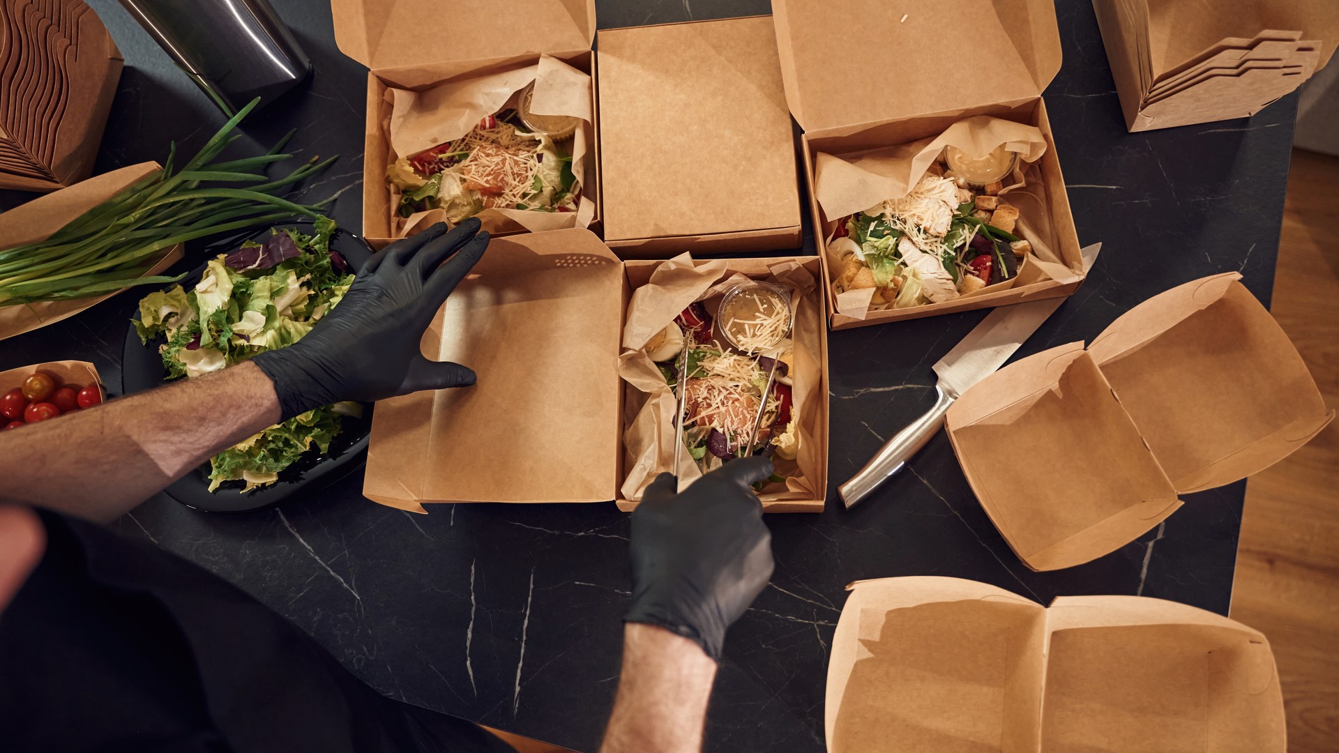 Cocinero prepara pedidos de comida para llevar en cajas de cartón en la cocina de un restaurante