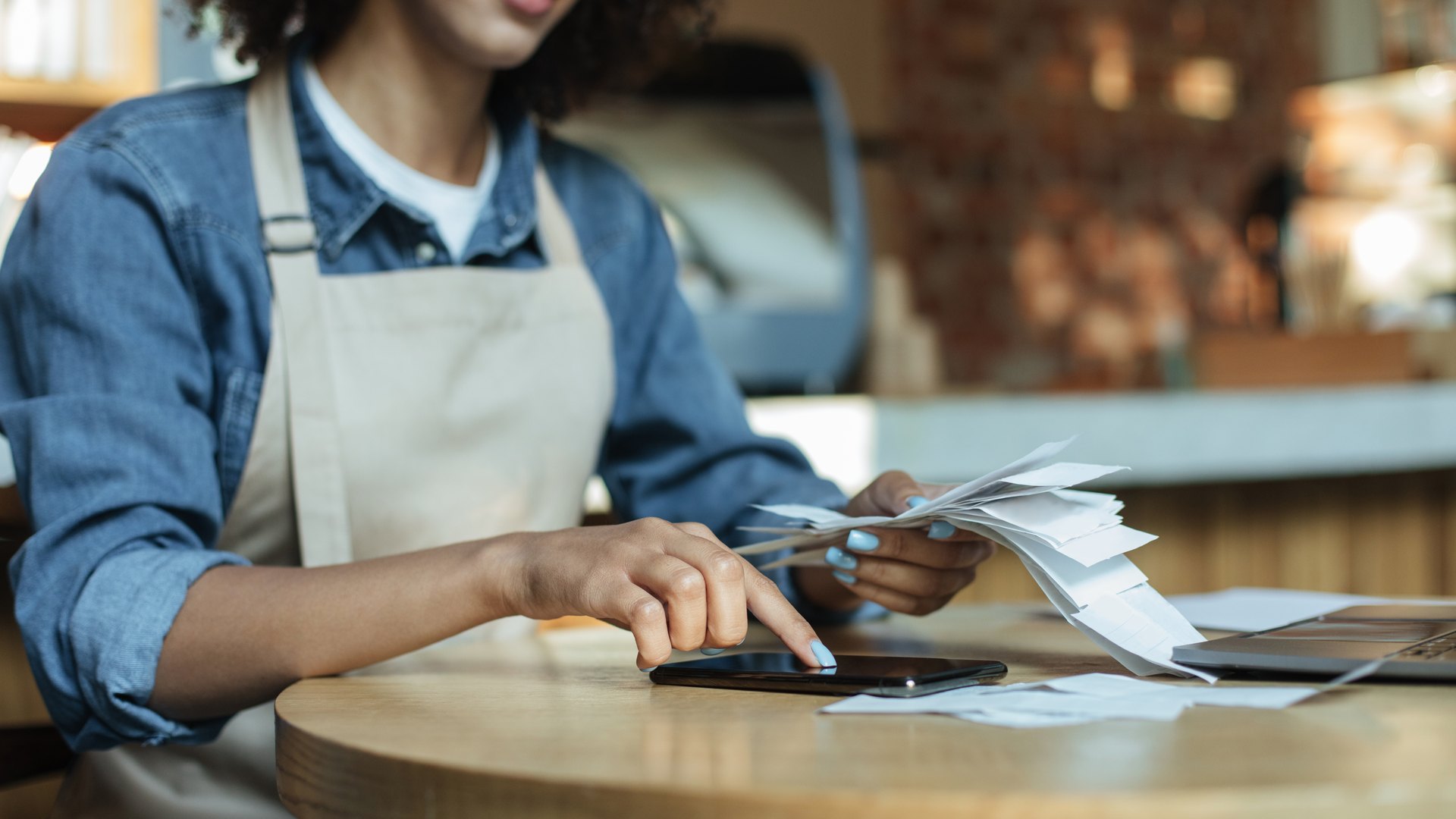 Propietaria calcula el punto de equilibrio de su restaurante con las cuentas sobre la mesa